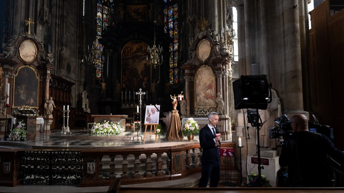 A crew of Austrian state television ORF report in front of a photo of Pope Francis on display in St. Stephen’s Cathedral in Vienna on April 21, 2025.