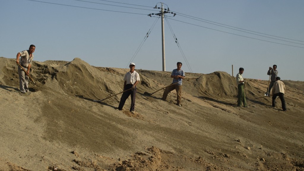 In a photo taken on August 19, 2012 workers stand on a roadside near a toxic lake surrounded by rare earth refineries near the city of Baotou, China.