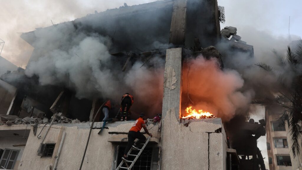 Civil defence personnel search a burning house targeted by Israeli airstrikes in Gaza City, on November 22, 2025.