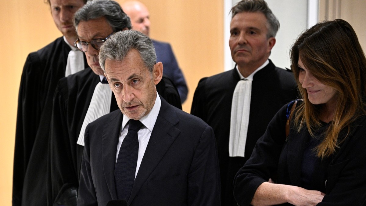 Former French president Nicolas Sarkozy (C) speaks to the press flanked by his wife Carla Bruni (R) and French lawyer Jean-Michel Darrois (2L) after the verdict in his trial for illegal campaign financing from Libya for his successful 2007 presidential bid, at the Tribunal de Paris courthouse in Paris, on September 25, 2025.