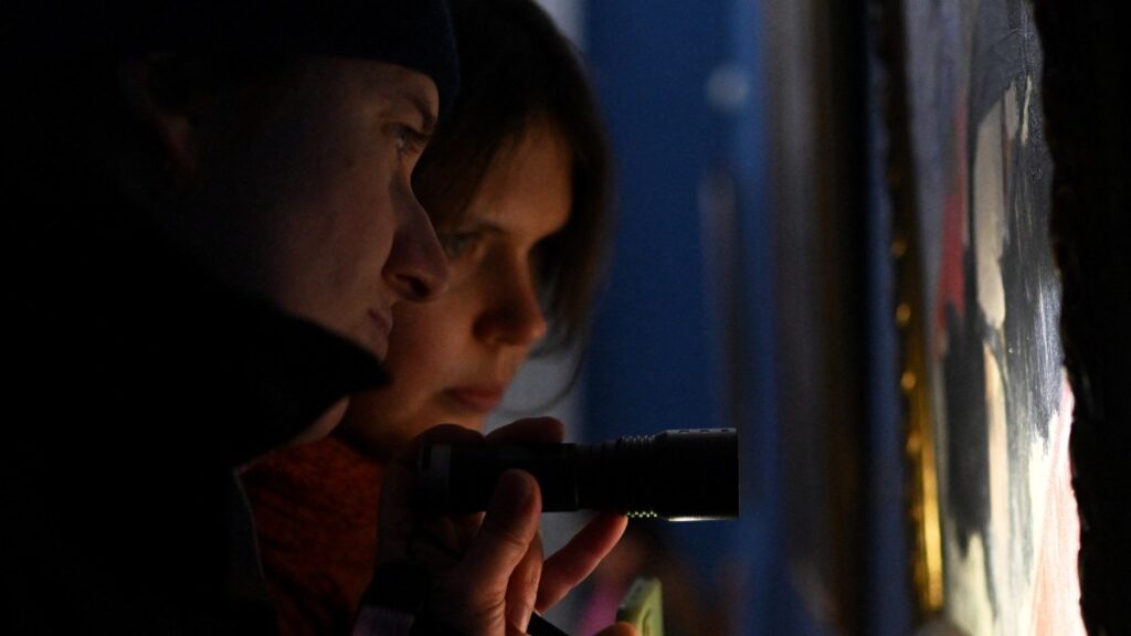 Visitors use a flashlight as they visit an exhibition during a power outage at the National Art Museum in Kyiv on January 30, 2026.