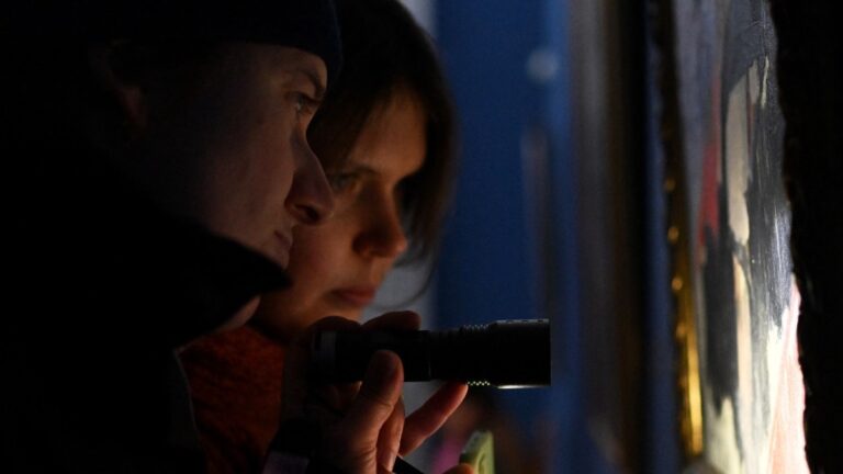 Visitors use a flashlight as they visit an exhibition during a power outage at the National Art Museum in Kyiv on January 30, 2026.