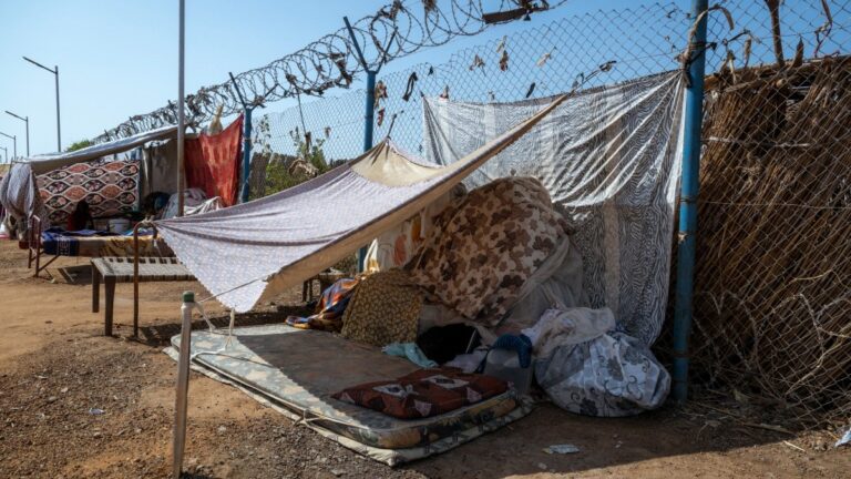 Makeshift shelters stand next to a fence at the Renk Transit Center in Renk, South Sudan, on November 18, 2025.