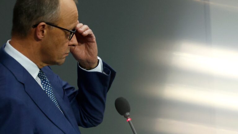 German Chancellor Friedrich Merz stands at a microphone during a question time at the Bundestag in Berlin on December 17, 2025.