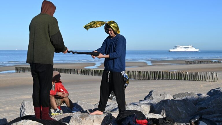 Migrants wring out clothes after being rescued following their unsuccessful attempt to cross the Channel in a inflatable boat near a beach in Sangatte, northwestern France on December 13, 2025.