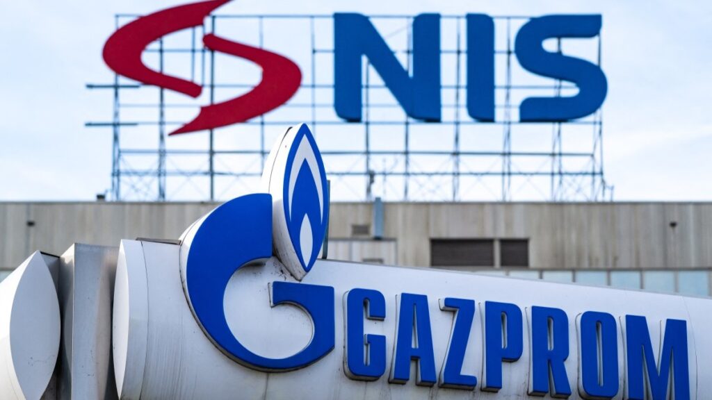 The logo of Naftna Industrija Srbije - NIS (Petroleum Industry of Serbia) displayed on the facade of the company's headquarters above the logo of a Gazprom gas station in Belgrade on November 25, 2025.