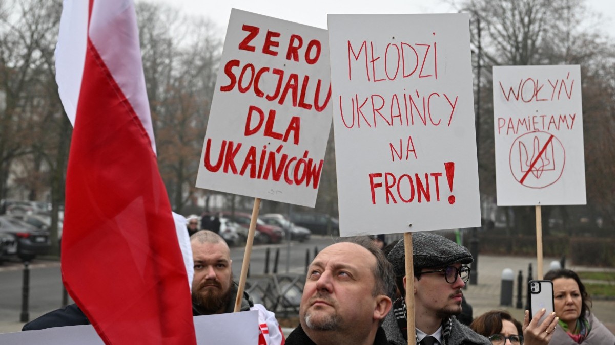 Demonstrators hold placards reading (L-R) “No social benefits for Ukrainians”, “Ukrainian youth, go to the front!”