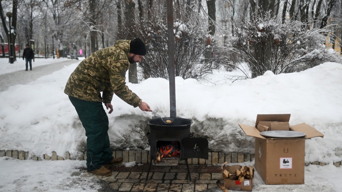 Volunteer Yevgen Gutman cooks baursak, a traditional Central Asian bread, on a potbelly stove at a heating point in a park in Kyiv on January 15, 2026.