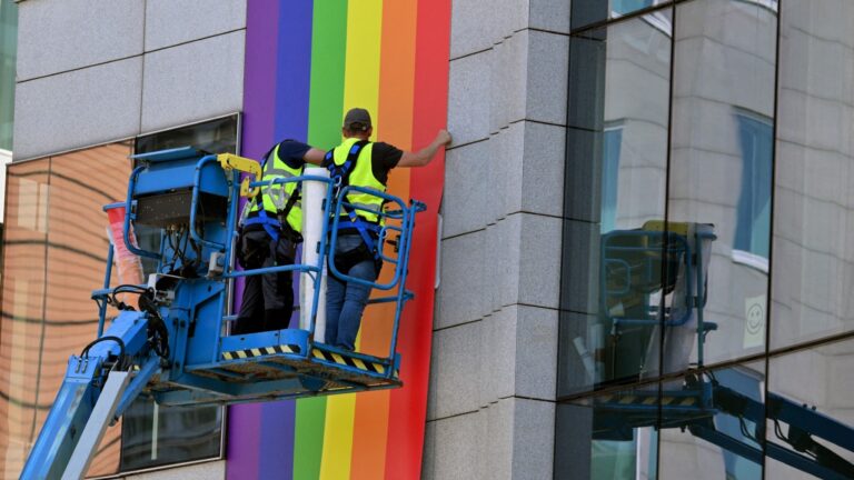 Workers put up giant LGBT flags on the facade of a building of the European Council on May 13, 2025 in Brussels, a few days ahead of the Brussels’ Pride.