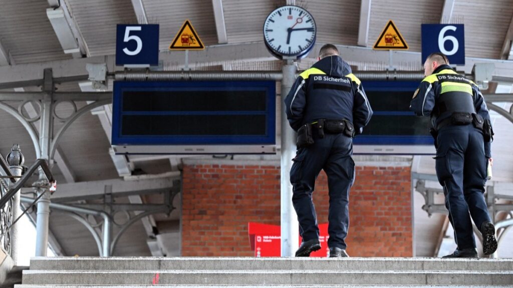 Security personnel of German railway operator Deutsche Bahn (DB) walk at the Wannsee S-Bahn train station, out of service following a major power otage in southwest Berlin on early January 4, 2026.