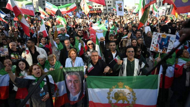 People celebrate the U.S.-Israeli strikes on the Islamic regime of Iran, holding Iranian pre-revolution Lion and Sun flags at the Potsdamer Platz in Berlin, Germany on February 28, 2026.