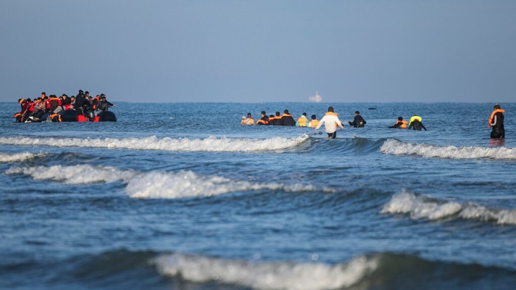 Migrants wade into the sea to try to board smugglers’ boats in an attempt to cross the English Channel off the beach of Gravelines in northern France on September 27, 2025.
