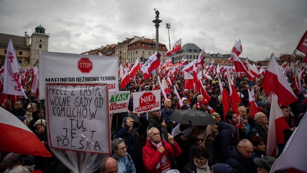 Demonstrators hold Polish national flags during an anti-government protest called by Poland’s nationalist Law and Justice (PiS) party on the Royal Castle Square in Warsaw, Poland, on October 11, 2025.
