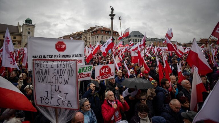 Demonstrators hold Polish national flags during an anti-government protest called by Poland’s nationalist Law and Justice (PiS) party on the Royal Castle Square in Warsaw, Poland, on October 11, 2025.
