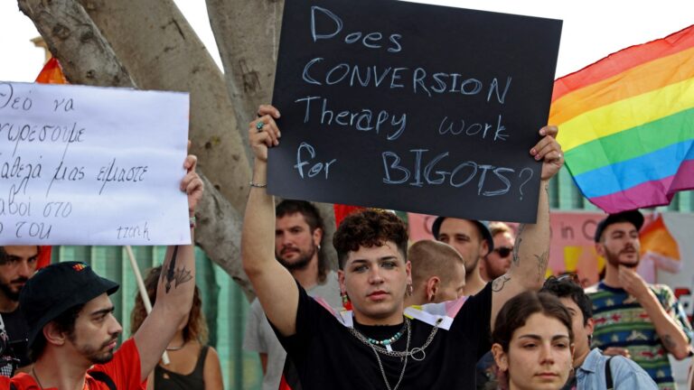A demonstrator waves a rainbow flag as activists protest outside the Cypriot parliament in Nicosia on May 25, 2023 over proposed amendments by the right-wing party Elam to a bill on the criminalisation of "gay conversion therapy."