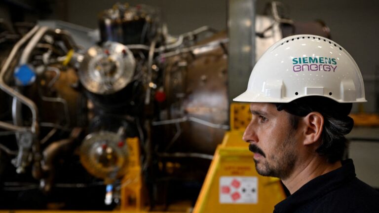 An employee of Siemens Energy stands on August 3, 2022 in front of a turbine of the Nord Stream 1 pipeline at the plant of Siemens Energy in Mülheim an der Ruhr, western Germany, where the engine is stored after maintenance work in Canada.