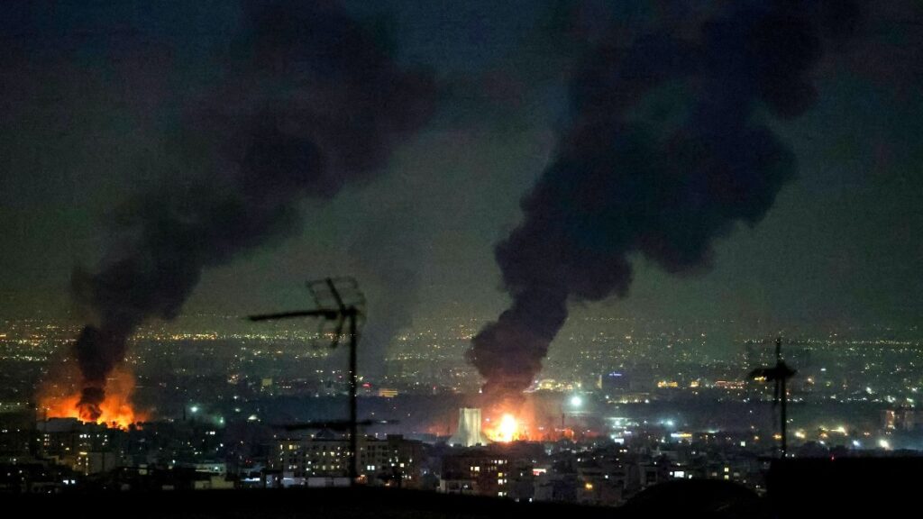 A tall plume of smoke billows from a fire next to Azadi Tower (C) following strikes near Mehrabad International Airport in Tehran on March 7, 2026.