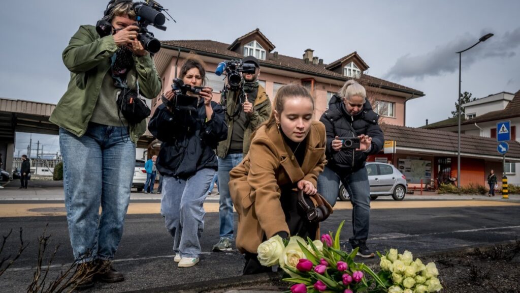 A young woman lays flowers on March 11, 2026 in Kerzers, western Switzerland where a bus caught fire on March 10, 2026, killing at least six people and injuring five others in what police said may have been a deliberate act.