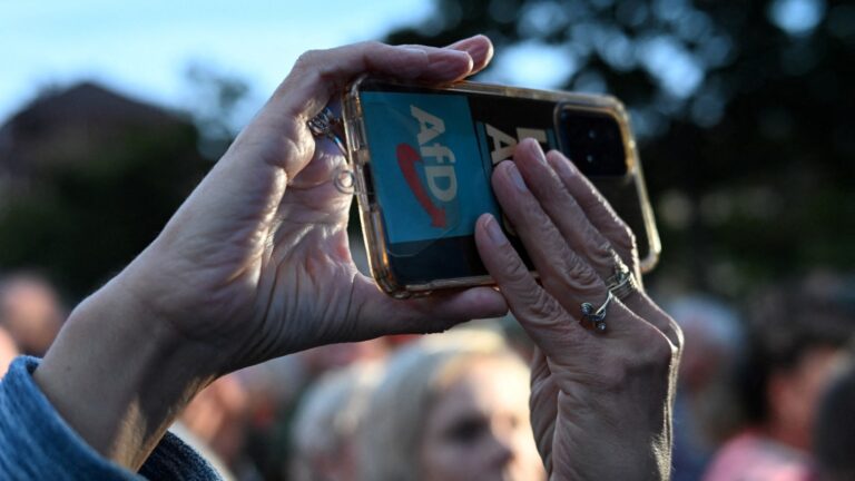 A supporter holds up a mobile phone with the party logo during an AfD rally, ahead of the regional elections in the eastern German state of Brandenburg, in Cottbus on September 19, 2024.