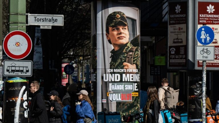 An advertising poster for the Bundeswehr is altered to read: “...and my hands are covered in blood,” in Berlin on March 22, 2026.