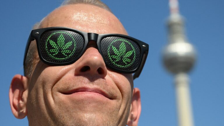 A participant in the annual Hemp Parade (Hanfparade), a demonstration in support of of hemp, wears cannabis themed sunglasses as they march in front of the landmark TV Tower in Berlin on August 9, 2025.