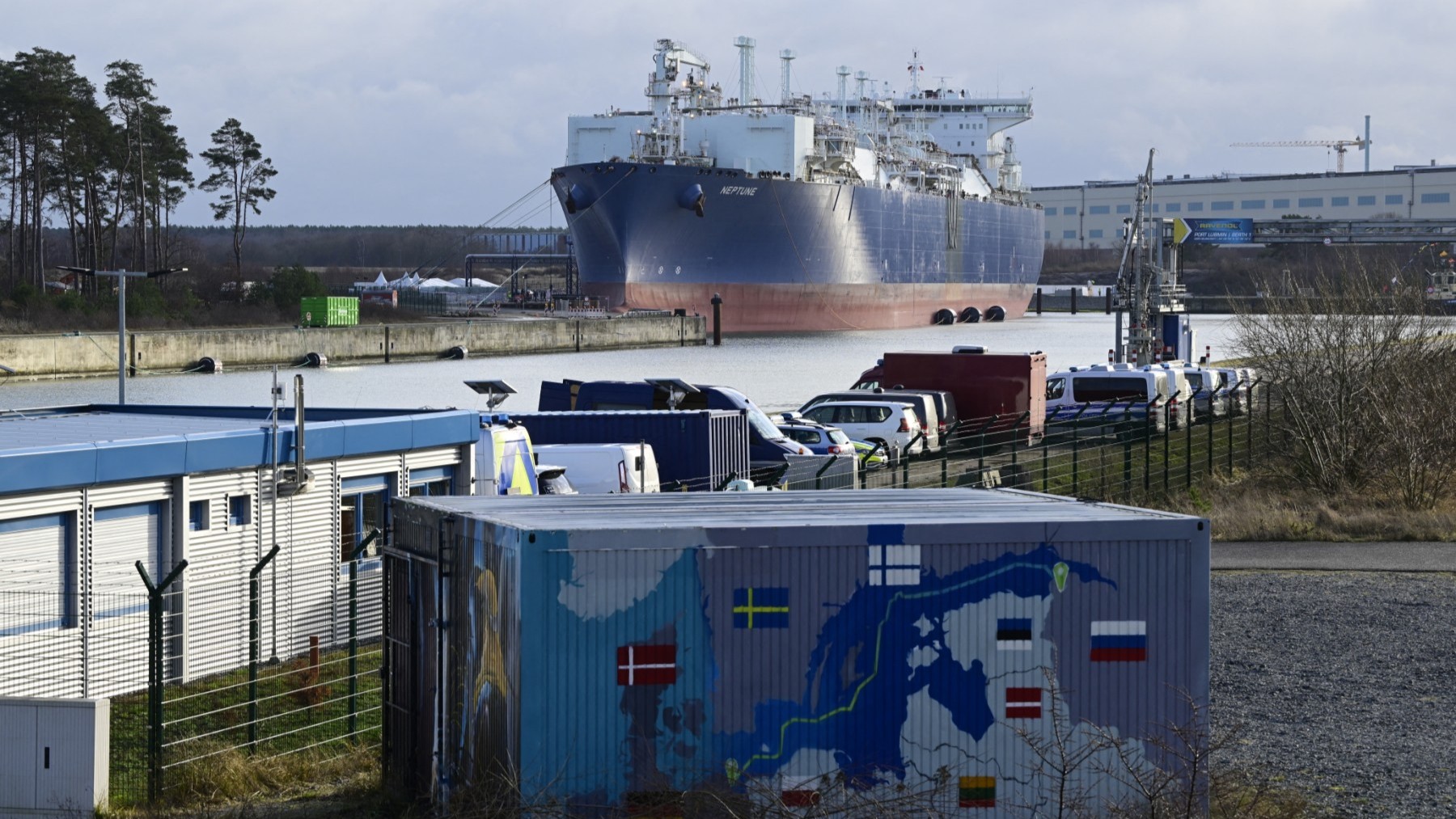 Floating Storage and Regasification Unit (FSRU) ‘Neptune’ is pictured behind a container painted with a map showing the Nord Stream 2 gas pipeline in Lubmin's industrial park, Germany, on January 14, 2023.