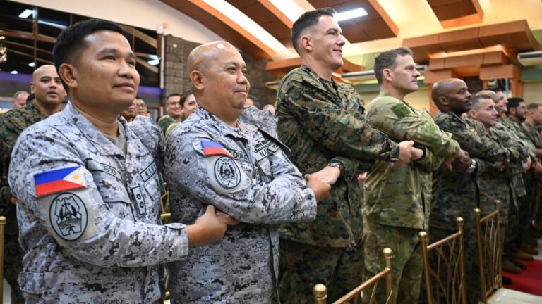 Philippine military officers (L) join hands with U.S. marines officers during the opening ceremony of the annual Balikatan joint military exercise at Camp Aguinaldo in Quezon city, suburban Manila on April 20, 2026.