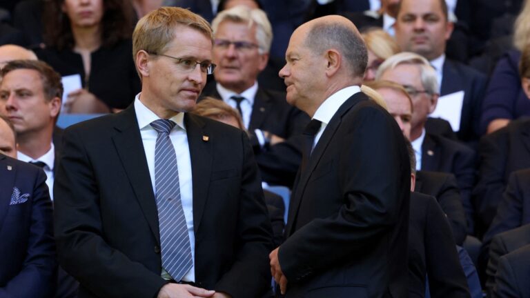 German Chancellor Olaf Scholz (R) and Schleswig-Holstein's State Premier Daniel Günther greet each other in the Volkspark stadium as they arrive for the funeral service for former German football player Uwe Seeler in Hamburg, northern Germany, on August 10, 2022.