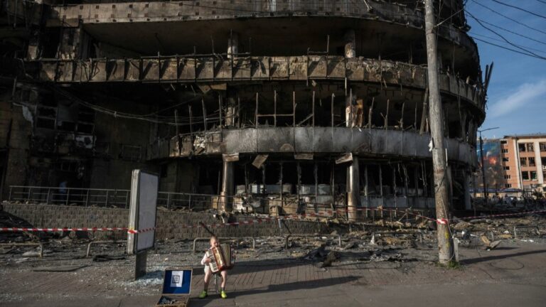 A boy plays the accordion in front of a shopping center damaged by Russian strikes in Kyiv on May 25, 2026.