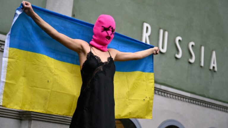 A member of the Pussy Riot activist group holds an Ukrainian flag during a protest against the participation of Russia in the Venice Biennale art show, in front of the Russian pavilion on May 6, 2026 in Venice.