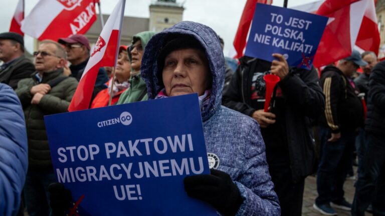 Participants hold Polish national flags and banners reading "Stop to the EU Migration Pact" and "This is Poland not a Caliphate" during an anti-migration protest in Warsaw on October 11, 2025.