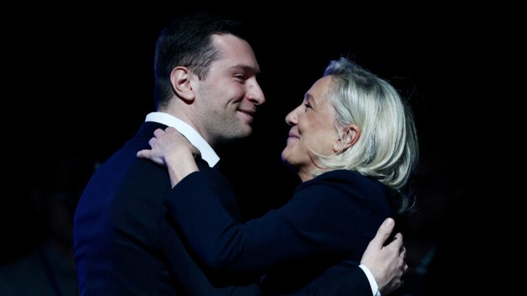 Rassemblement National RN party’s President Jordan Bardella and the President of the party’s parliamentary group Marine Le Pen embrace during a party rally following the results of the first round of France's 2026 municipal elections, in Chalons-en-Champagne, on March 18, 2026.