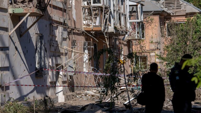 Ukrainian law enforcement officers work next to a damaged residential building following an air attack in Dnipro on June 2, 2026.