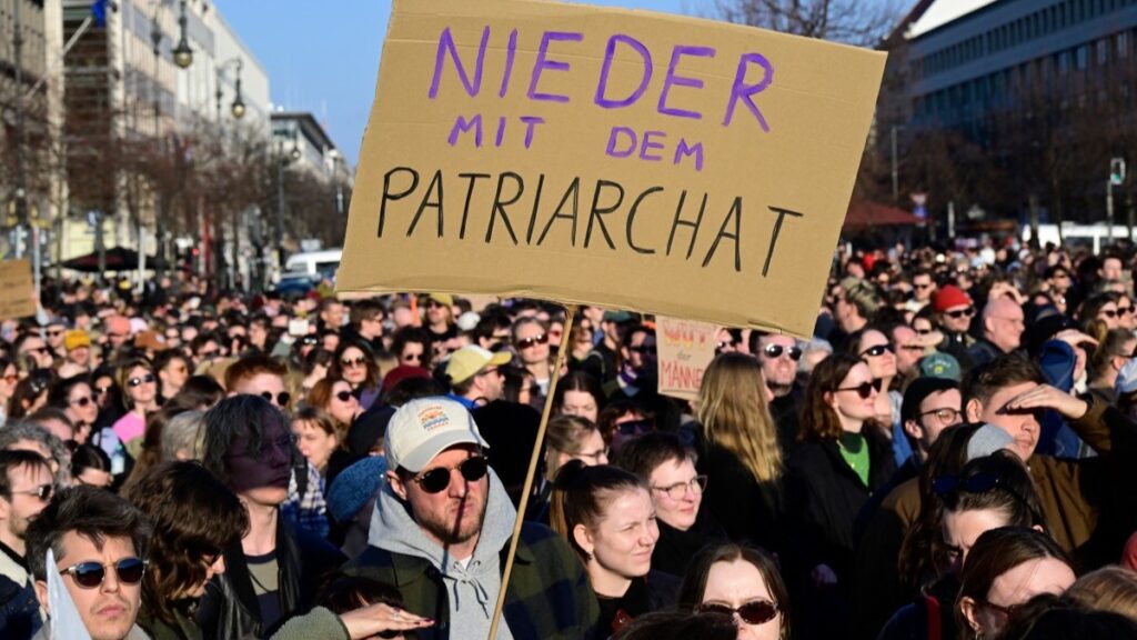 Protesters hold up a placard reading "Down with patriarchy" as they take part in a demonstration organised by the action group "Feminist Fight Club" on March 22, 2026 at the Brandenburg Gate in Berlin.