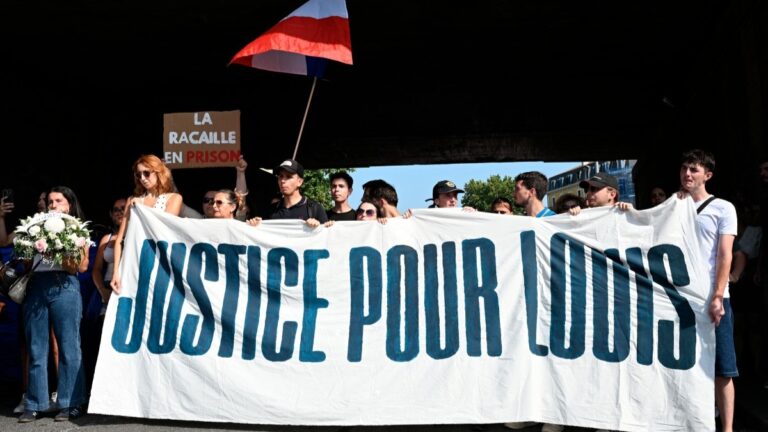 People hold a national flag and a banner reading “Justice for Louis ” during a rally in the memory of Louis, a 17-year-old boy who died after being beaten up by five young people during an ambush, in Narbonne, southern France, on June 28, 2026.