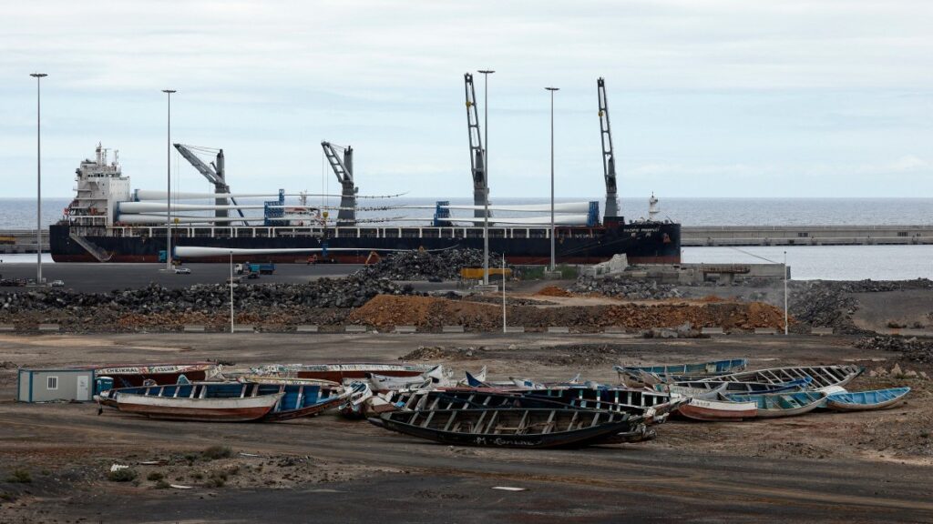 A large cargo ship is seen behind migrant boats stacked at the port of Granadilla de Abona, on the island of Tenerife in Spain’s Canary Islands on May 6, 2026.