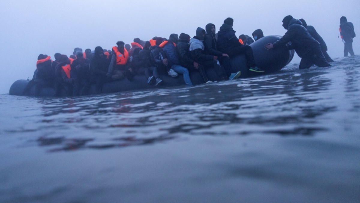 Smugglers assist migrants to board a boat in an attempt to cross the English Channel off the beach of Gravelines, northern France, on March 4, 2026.