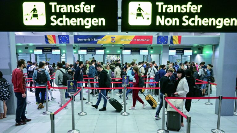 Travelers walk next to newly installed signs pointing to Schengen and non-Schengen areas minutes after midnight, just after Romania’s official entry into the European area of free circulation at Otopeni's international airport on March 31, 2024.
