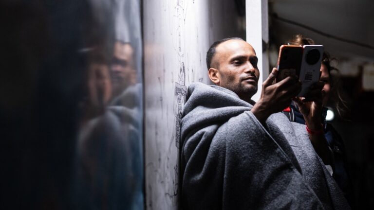 A migrant films as other dance while celebrating on the eve of their arrival to Italy onboard the rescue ship "Ocean Viking" operated by the NGO SOS Mediterranee,