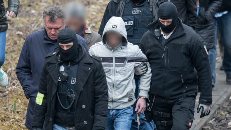 Defendant Ali B (C), the Iraqi man accused of the rape and murder of teenage girl Susanna, is escorted by masked police officers during a revisiting of the crime scene in Erbenheim near Wiesbaden, western Germany, on March 27, 2019.