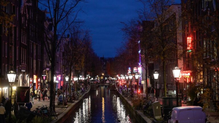 People walk on docks at night in the red quarter in Amsterdam, western Netherlands, on November 24, 2021.