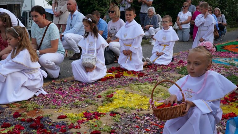 Children holding baskets with petals kneel next to a flower carpet during a Corpus Christi procession in Spycimierz, Poland, on June 16, 2022.