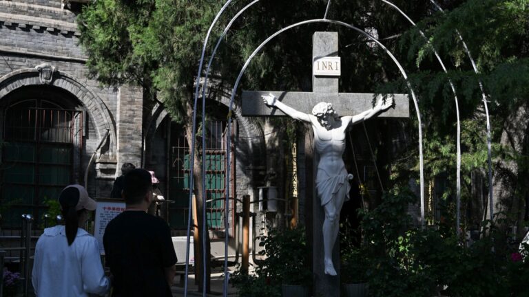 A couple looks at a crucifix outside a Catholic church in Baoding, China’s northern Hebei province on April 22, 2025.