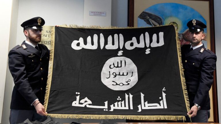 Italian police officers display a confiscated Islamic State (IS) flag during a press conference at the police headquarters in Romeo n January 10, 2017.