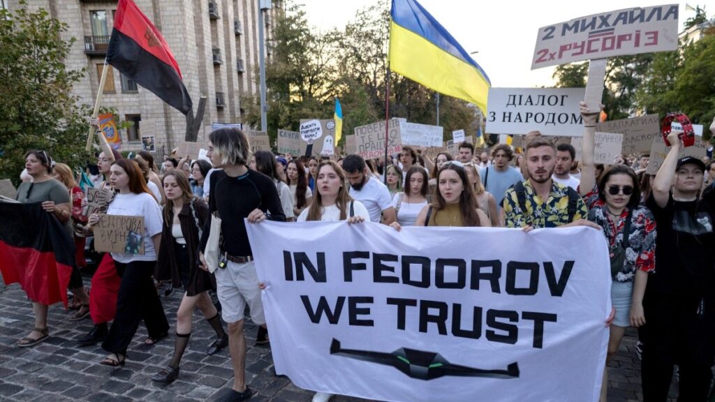 Protesters carry placards as they march demanding a reform of the defence sector and the reinstatement of defence minister Mykhailo Fedorov, replaced a mounth ago, in central Kyiv on August 16, 2026.