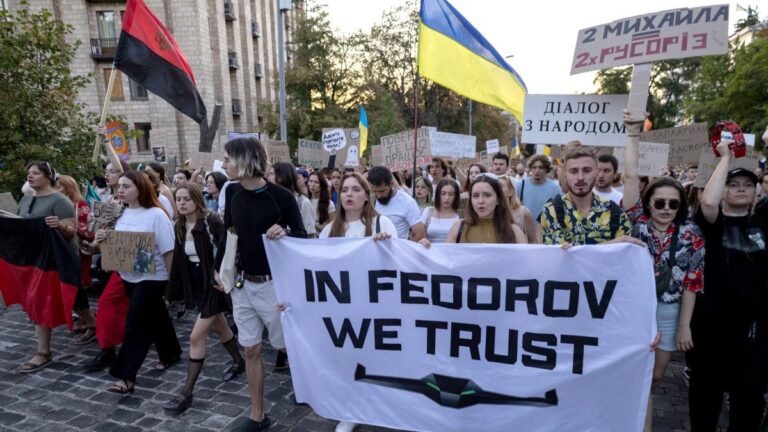 Protesters carry placards as they march demanding a reform of the defence sector and the reinstatement of defence minister Mykhailo Fedorov, replaced a mounth ago, in central Kyiv on August 16, 2026.