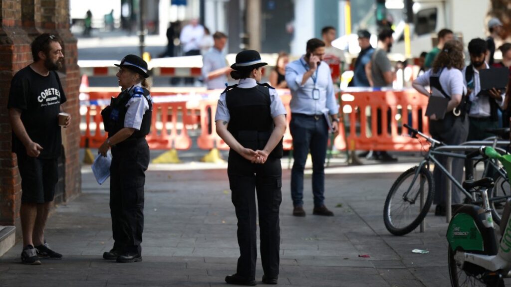 Police community support officers (PCSOs) stand behind cordon tape at Endell road in Covent Garden, central London on August 5, 2026.