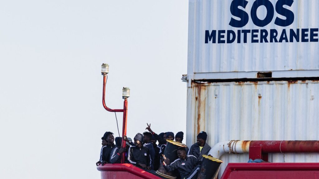 Migrants on the deck of rescue ship Ocean Viking operated by the NGO SOS Méditerranée wave to a Search and Rescu (SAR) team off the coast of Libya, on January 17, 2026.Â