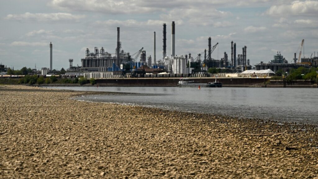 A vessel sails past the partially dried-up river bed of the Rhine at the Shell Energy and Chemicals Park Rheinland – Nord in Godorf near Cologne, Germany on August 7, 2026, following exceptionally hot weather.
