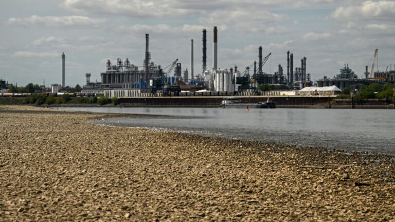 A vessel sails past the partially dried-up river bed of the Rhine at the Shell Energy and Chemicals Park Rheinland – Nord in Godorf near Cologne, Germany on August 7, 2026, following exceptionally hot weather.